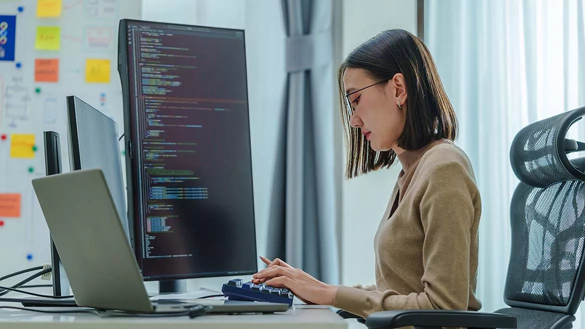 Asian prompt engineer develop coding app with software data sitting in front of computer monitor at office