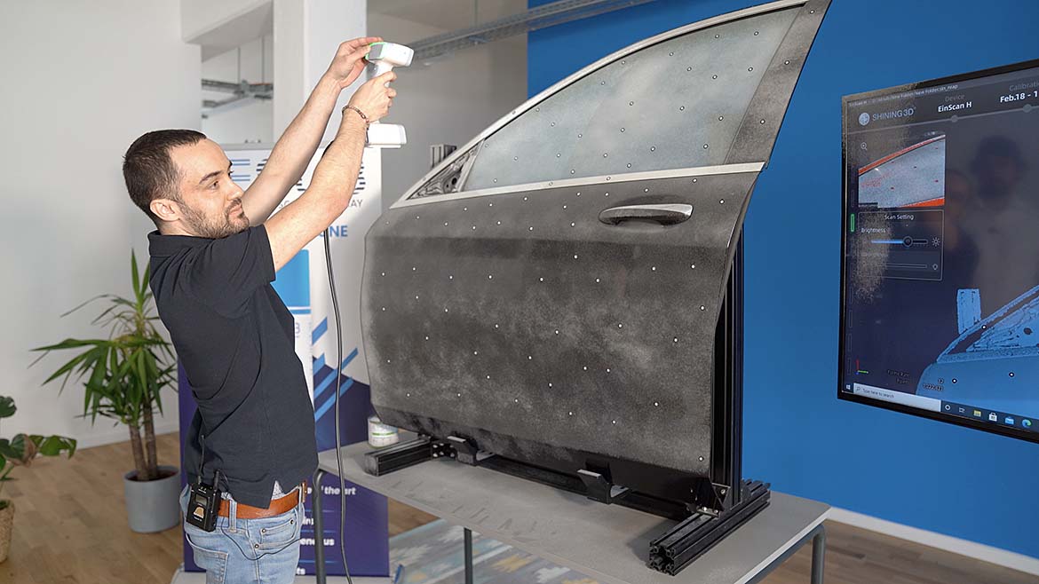 Worker prepares a car door for scanning process.