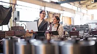 Female professionals discuss manufacturing infrastructure investment project in modern factory.