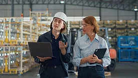 a stock photo of a young Caucasian female worker and a mature female manager in a retail warehouse.
