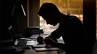 a silhouette of a person studying at a desk