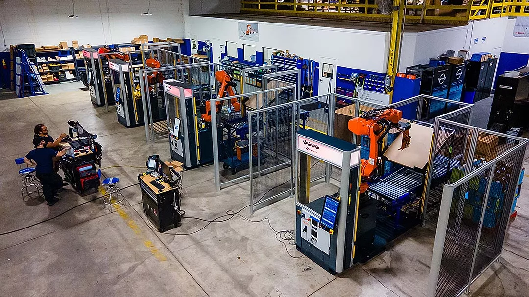 The image displays a robotic palletizing cell, an automated system used in manufacturing and logistics for stacking products onto pallets