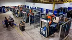 The image displays a robotic palletizing cell, an automated system used in manufacturing and logistics for stacking products onto pallets