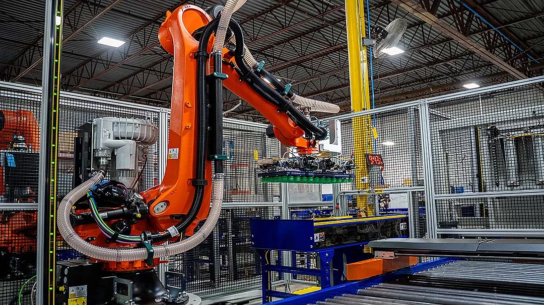 The image shows a KUKA industrial robot operating within an automated manufacturing facility