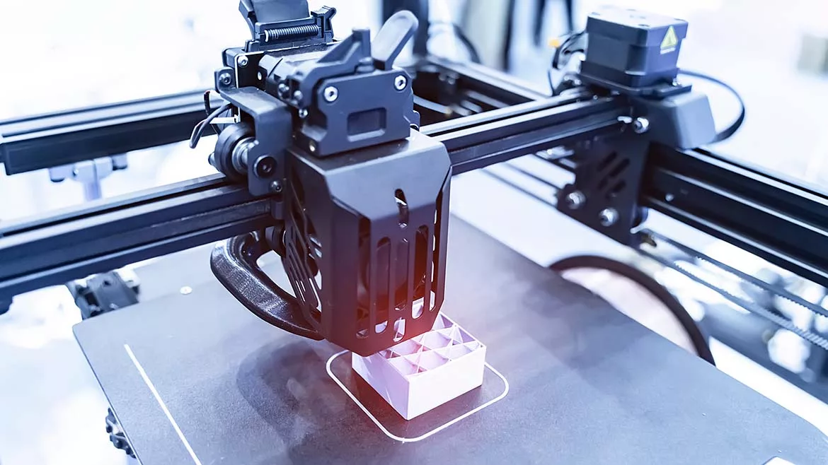 a 3D printer in operation, an additive manufacturing process that builds three-dimensional objects layer by layer from a digital file. 