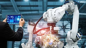 The image illustrates industrial robotic automation controlled by a manager or engineer using a tablet.