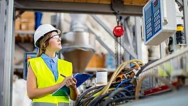 The image depicts a young female quality controller in a factory setting
