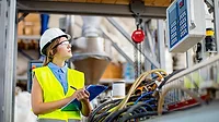 The image depicts a young female quality controller in a factory setting The image depicts a young female quality controller in a factory setting