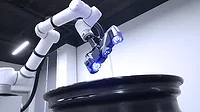 This image shows an automated industrial inspection system using a KSCAN-E 3D scanner mounted on a robotic arm. 