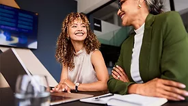 This image shows two people in a professional setting, likely discussing a business topic. 