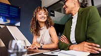 This image shows two people in a professional setting, likely discussing a business topic. 