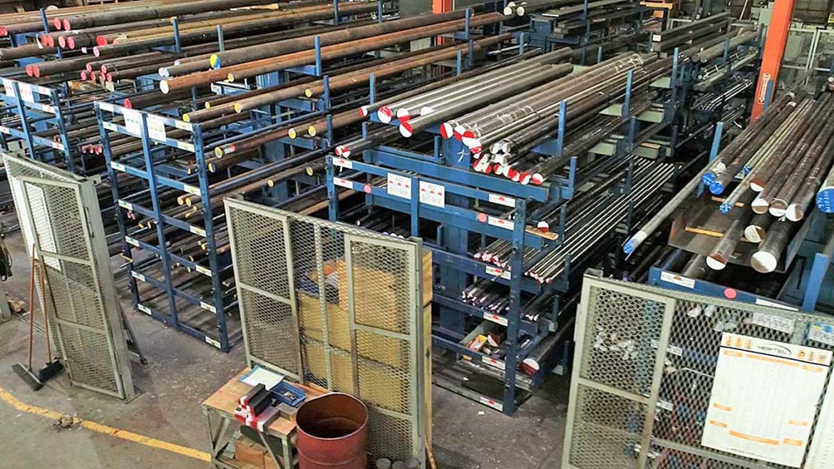 This image displays an industrial warehouse with cantilever racking systems used for storing long, heavy materials like steel bars and pipes