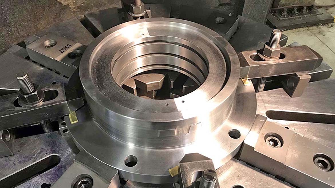 This is a large metal component being precision machined on a vertical turret lathe