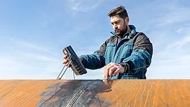 The image shows a technician performing ultrasonic testing (UT), a non-destructive testing (NDT) method