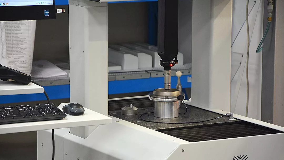 The image displays a Coordinate Measuring Machine (CMM), a specialized tool used for precise inspection and dimensional verification of manufactured parts.