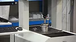 The image displays a Coordinate Measuring Machine (CMM), a specialized tool used for precise inspection and dimensional verification of manufactured parts. 