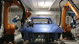 This image shows an automated automotive production line utilizing KUKA robots for surface processing and quality control on a vehicle body. 
