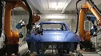 This image shows an automated automotive production line utilizing KUKA robots for surface processing and quality control on a vehicle body. 