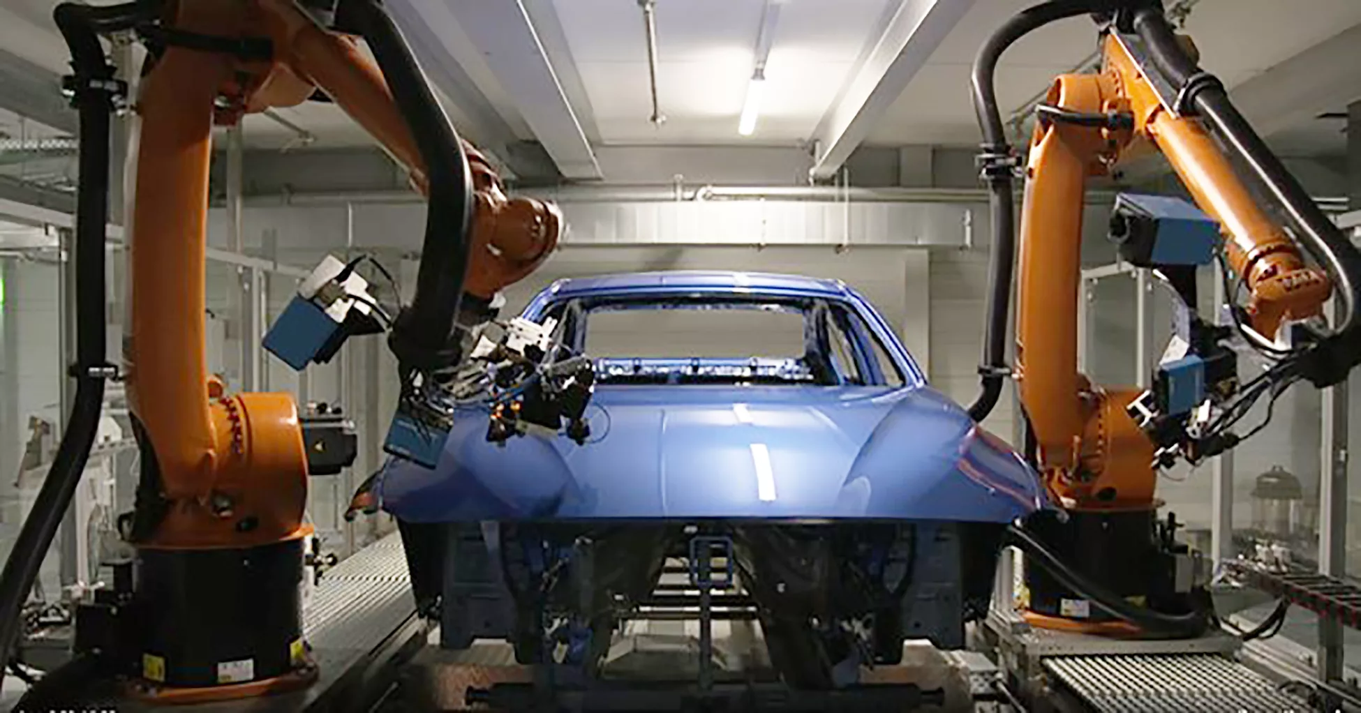 This image shows an automated automotive production line utilizing KUKA robots for surface processing and quality control on a vehicle body.