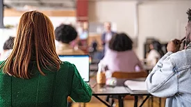 This image depicts a college classroom scene with students engaged in learning. 