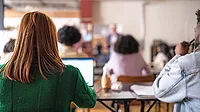 This image depicts a college classroom scene with students engaged in learning. 