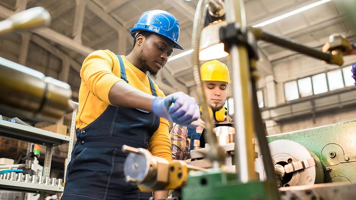 This image depicts a manufacturing engineer or machine operator working in an industrial setting.