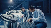 The image depicts engineers working on the development and safety testing of an electric vehicle chassis