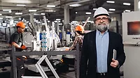 This image shows a middle-aged male manager or engineer wearing a white hard hat and glasses This image shows a middle-aged male manager or engineer wearing a white hard hat and glasses