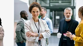 a businesswoman posing confidently in a modern office or conference setting.