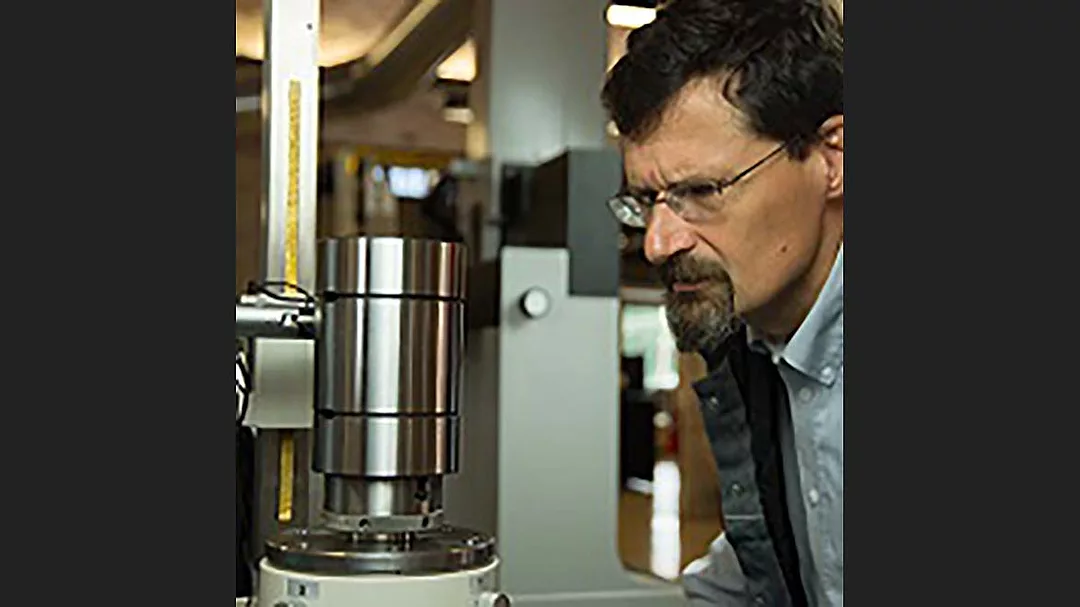 a person closely observing a metallic industrial component, possibly during a quality control or manufacturing process. 