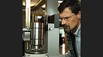 a person closely observing a metallic industrial component, possibly during a quality control or manufacturing process. 