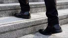 a person wearing black leather Chelsea boots while walking up stairs. 