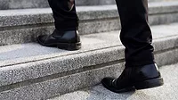 a person wearing black leather Chelsea boots while walking up stairs. 
