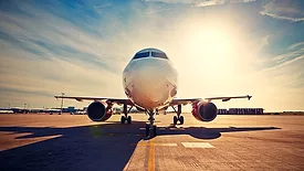 a commercial passenger aircraft parked on an airport tarmac during sunrise or sunset