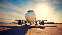 a commercial passenger aircraft parked on an airport tarmac during sunrise or sunset