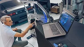 a person using a handheld Creaform 3D scanner to inspect a car door panel