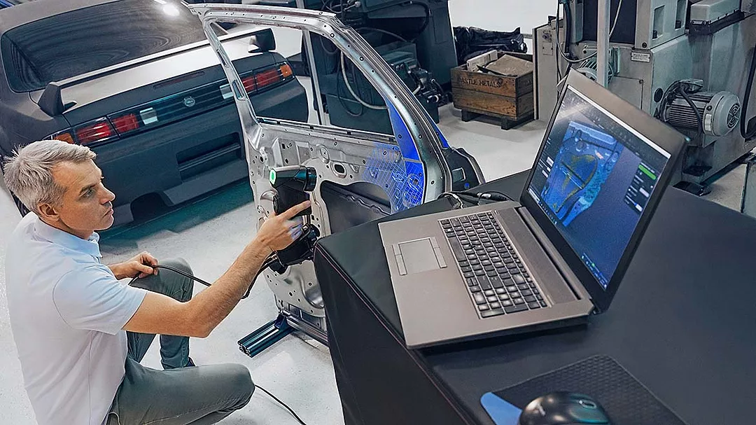 a person using a handheld Creaform 3D scanner to inspect a car door panel