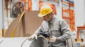 a senior technician inspecting large industrial metal coils