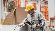 a senior technician inspecting large industrial metal coils