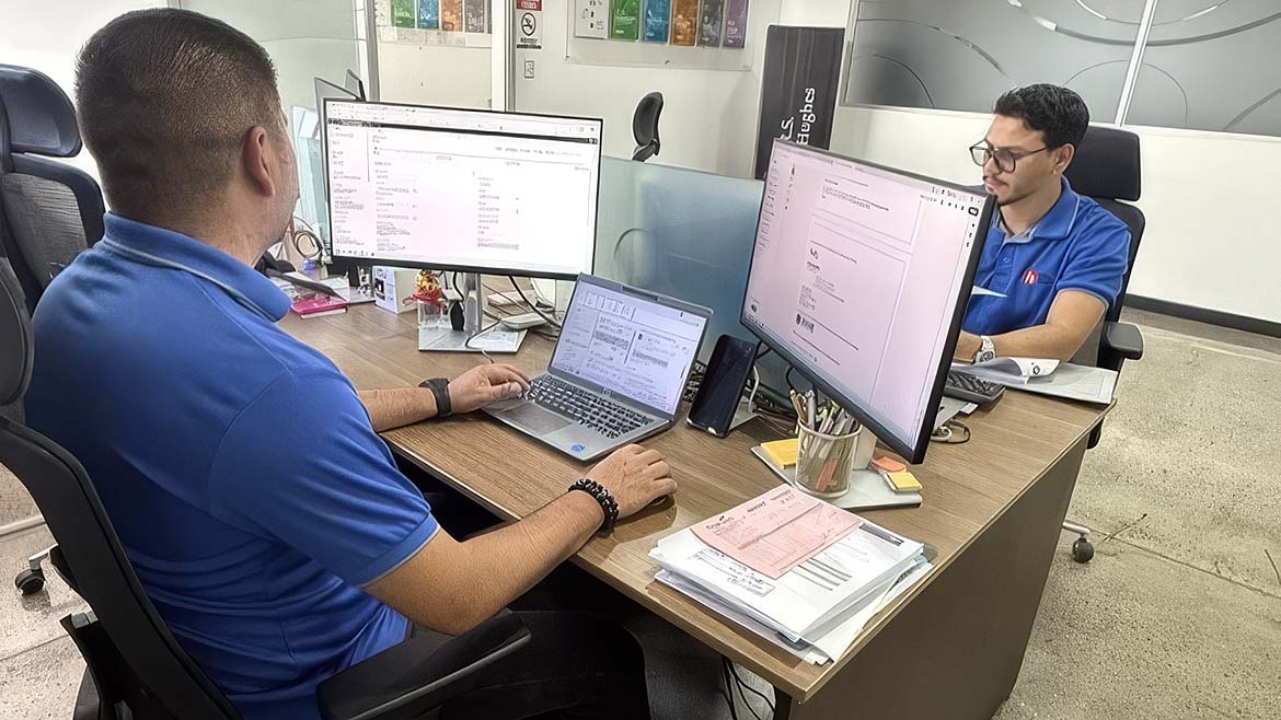an office setting with individuals working at their desks, focusing on computer monitors and laptops