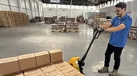 a yellow pallet jack being used in a warehouse setting a yellow pallet jack being used in a warehouse setting