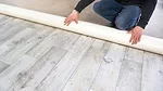 a person installing or rolling out sheet vinyl flooring