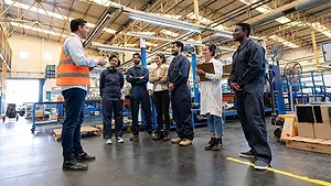 a factory floor during what appears to be a training session or a daily briefing