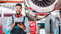 an aircraft technician smiling while using a digital tablet for maintenance tasks an aircraft technician smiling while using a digital tablet for maintenance tasks