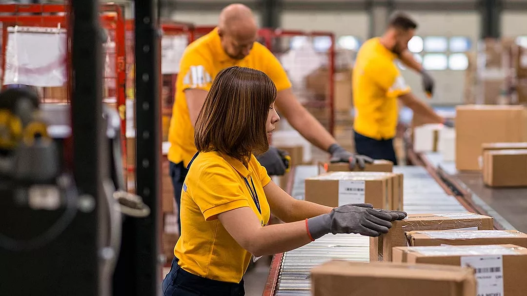 warehouse workers packing boxes on a conveyor belt