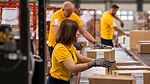 warehouse workers packing boxes on a conveyor belt