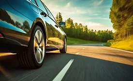 Passenger vehicle driving on a paved road, representing automotive performance, durability testing, and real-world driving conditions.