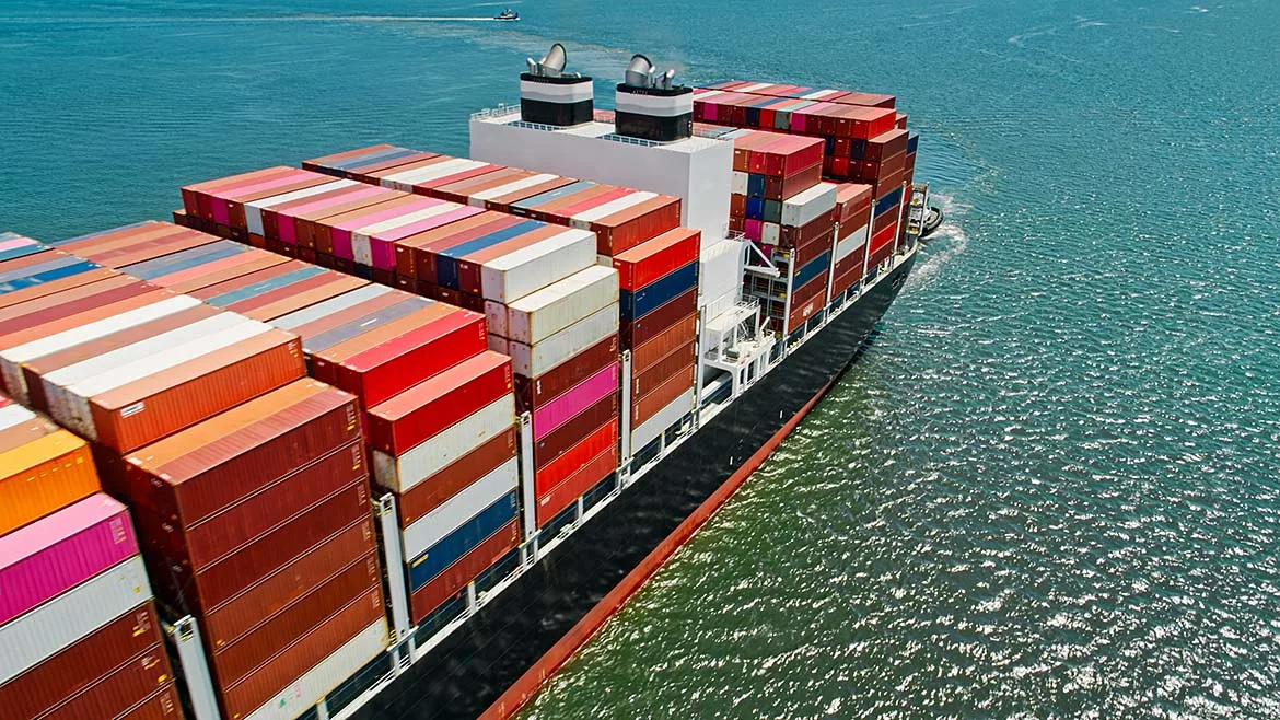 a massive container ship loaded with cargo containers traversing open water.