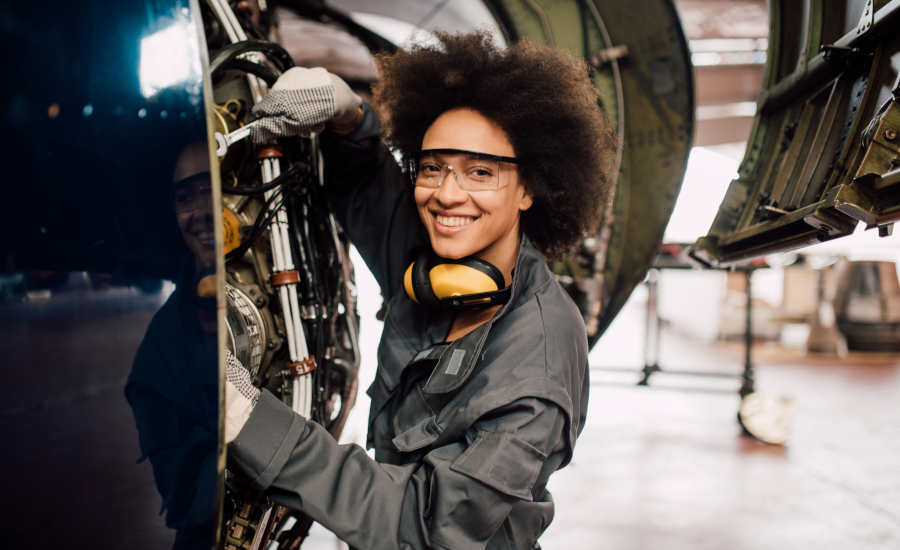 smiling woman working on an airplane engine