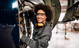 smiling woman working on an airplane engine